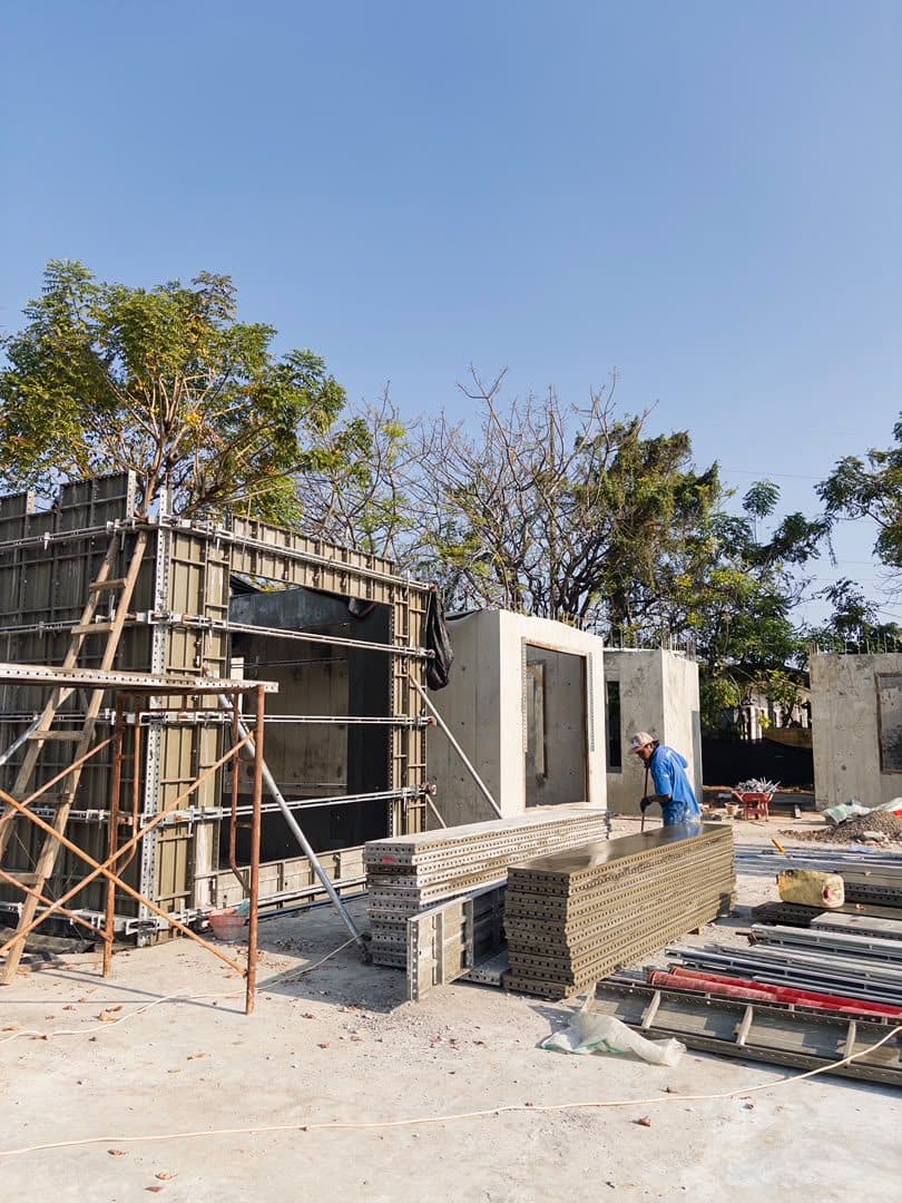 Worker beside formwork and scaffolding on a villa under construction